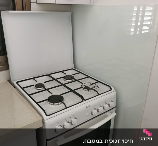 מגן זכוכית שקוף מאחורי כיריים במטבח
